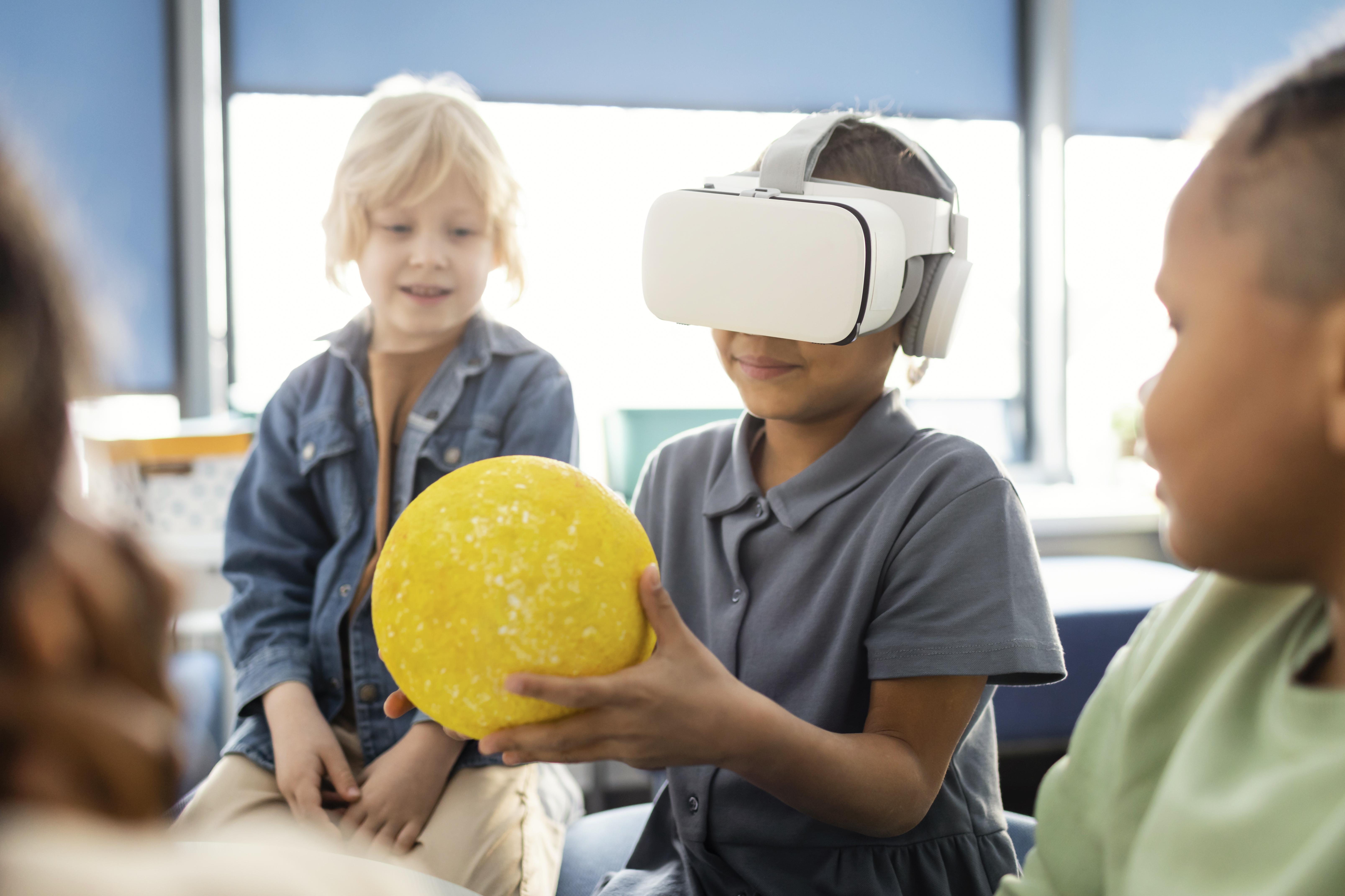 Várias crianças interagem em uma atividade, possivelmente envolvendo realidade virtual.
